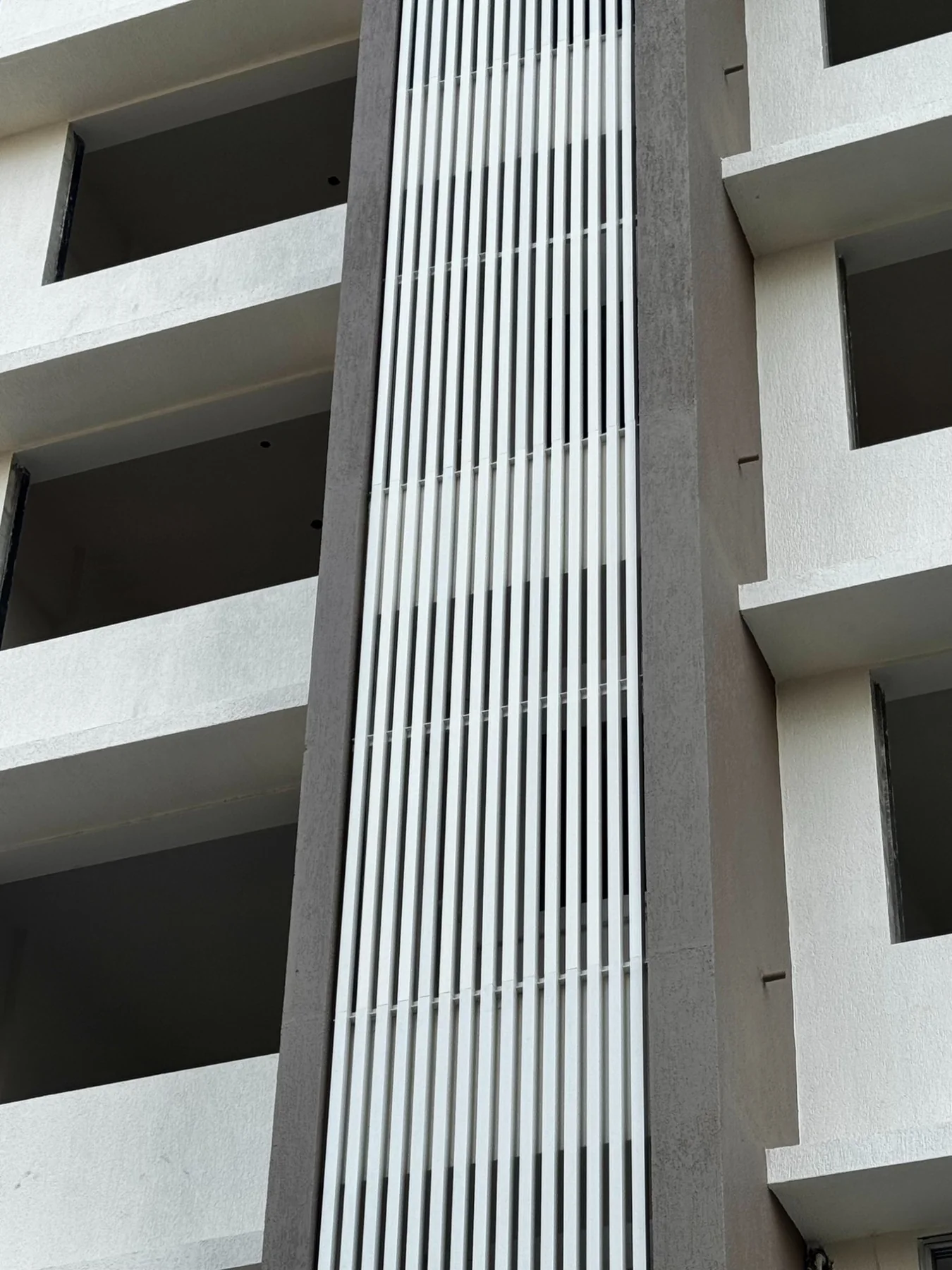 Close-up of square-profile UPVC fins set in a concrete facade column